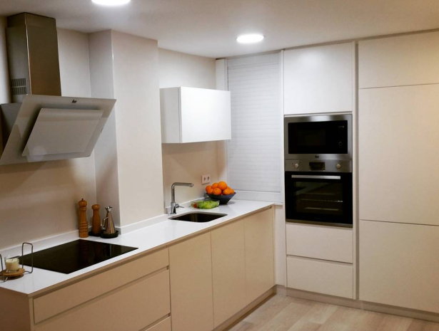 Cocina a medida en Elche de estilo moderno, con muebles blancos sin tiradores, electrodomésticos integrados y encimera clara.