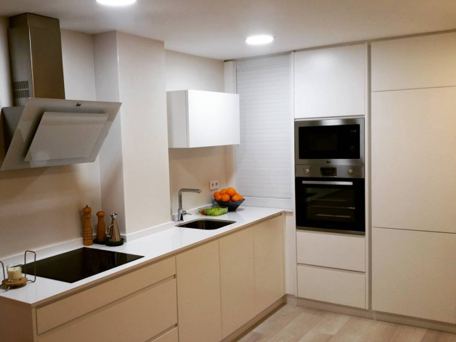 Cocina a medida en Elche de estilo moderno, con muebles blancos sin tiradores, electrodomésticos integrados y encimera clara.