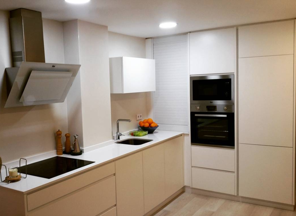 Cocina a medida en Elche de estilo moderno, con muebles blancos sin tiradores, electrodomésticos integrados y encimera clara.